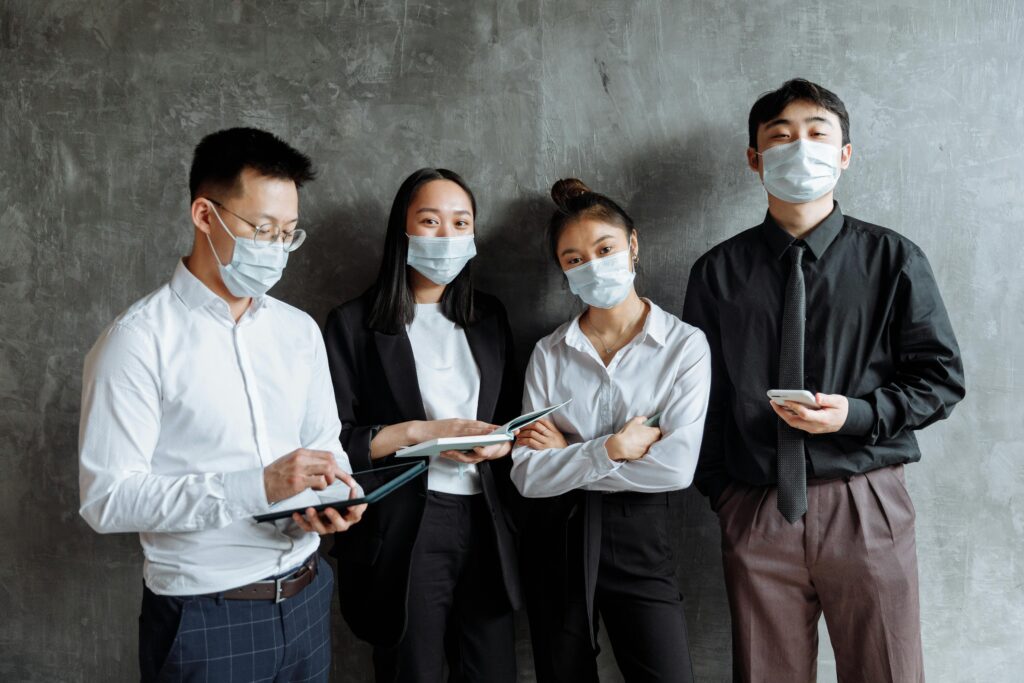 A group of professionals in a meeting wearing face masks, reflecting the new normal work environment.