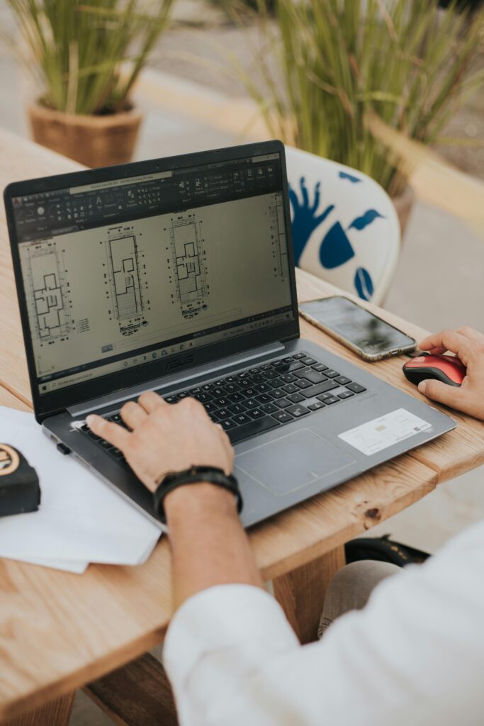 An architect working on building designs using a laptop outdoors, highlighting modern architecture.