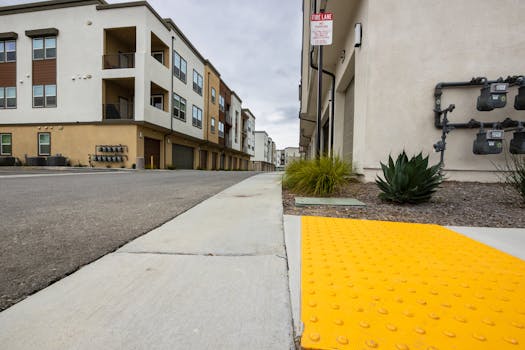 Yellow tactile paving on a modern city sidewalk for accessibility in urban areas.
