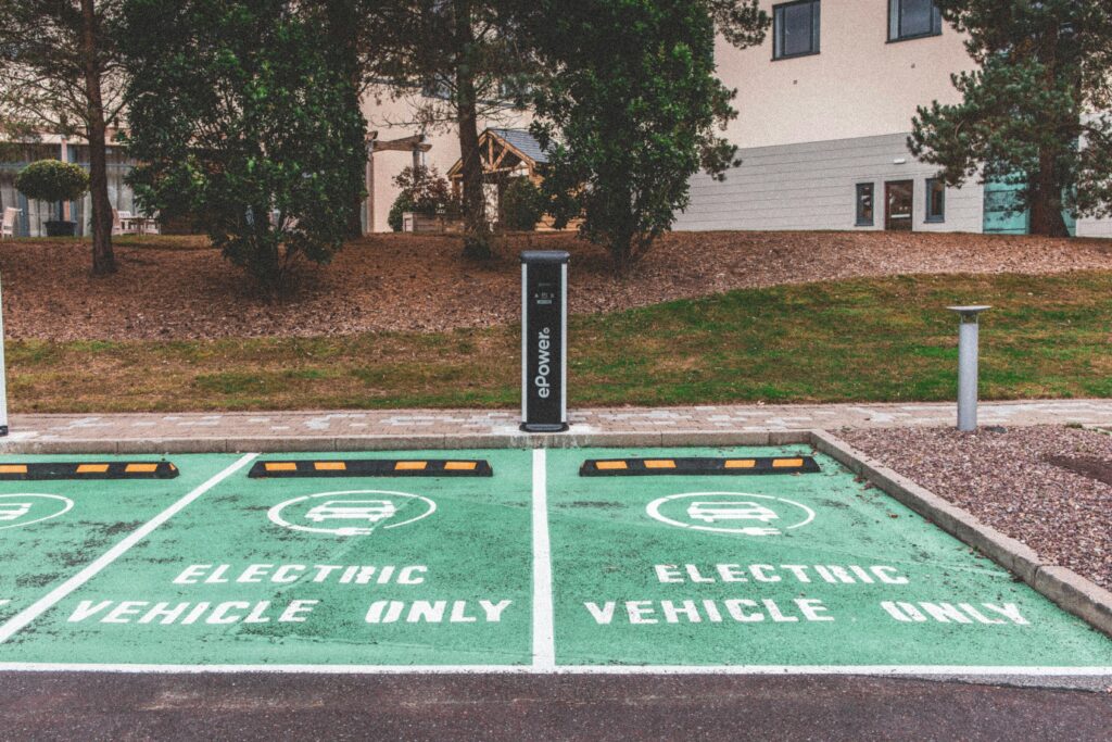 Green electric vehicle parking with charging station in urban environment.