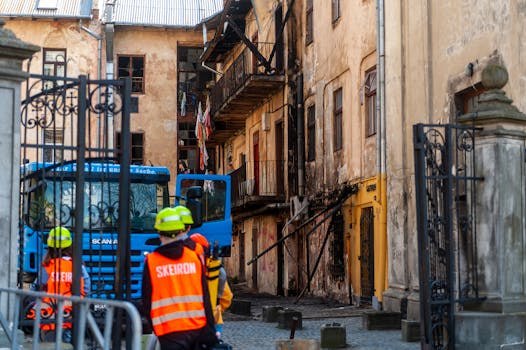 Fire damage inspection of old building in Lviv, Ukraine, with emergency responders present.