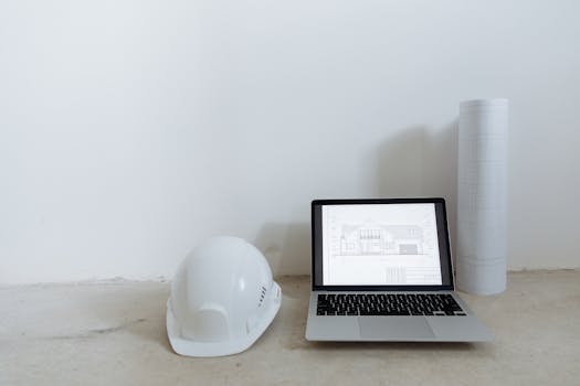 A clean workspace with laptop, hard hat, and blueprints for construction planning.
